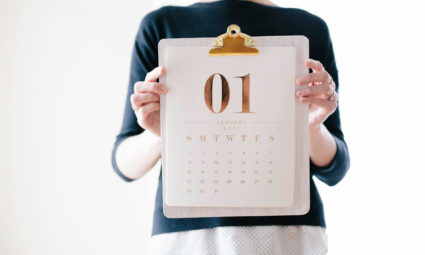 A woman holding up a calendar for the month of January